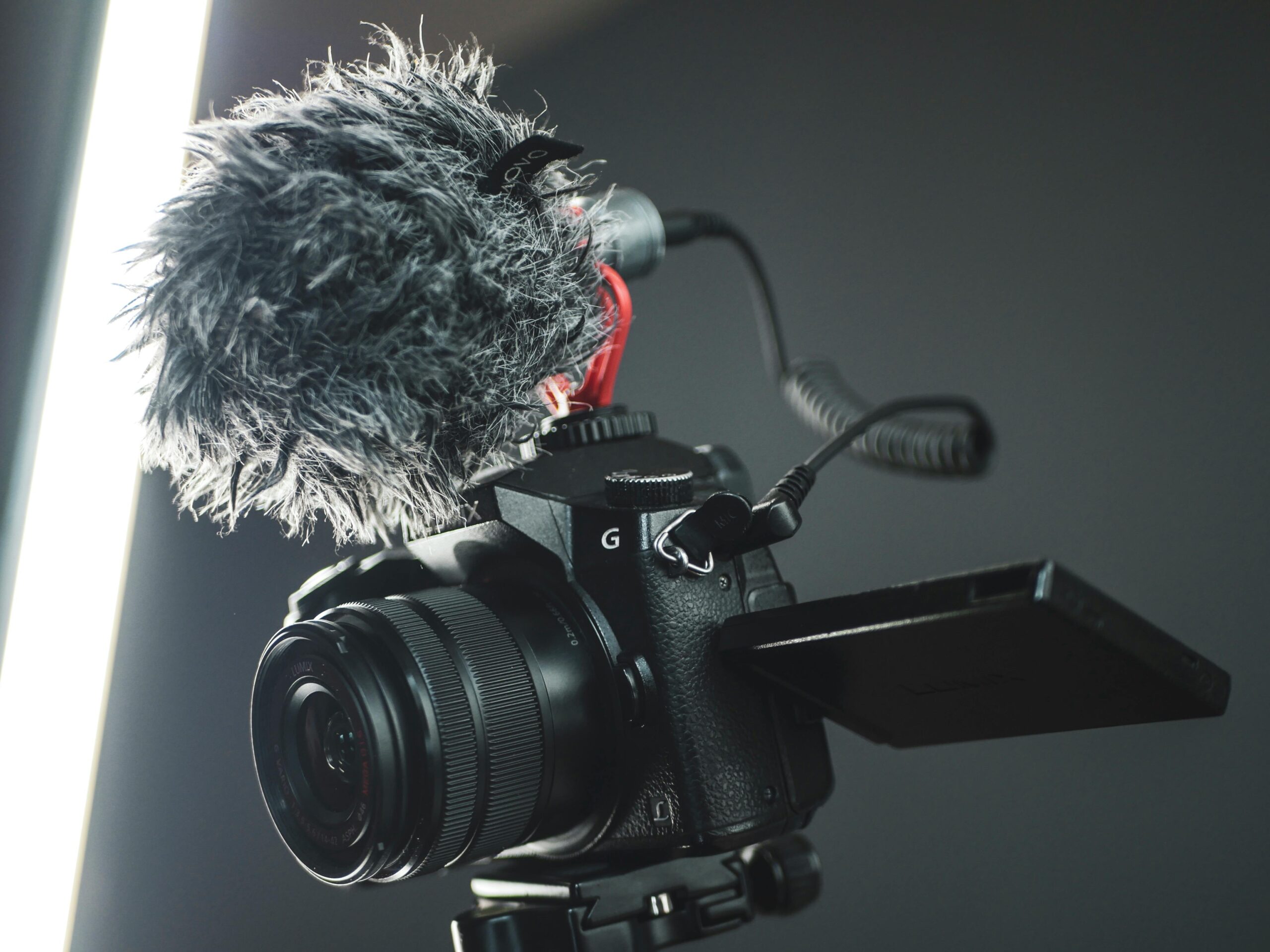 Close-up of a modern camera with external microphone in a studio setting.
